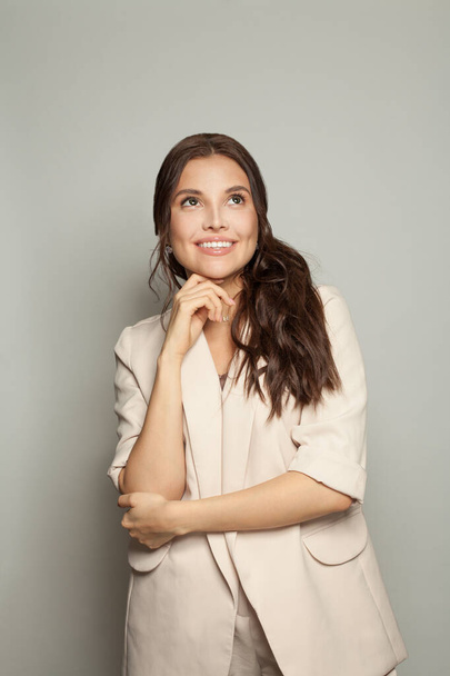 Šťastná brunetka podnikatelka v béžovém obleku s úsměvem na bílém pozadí - Fotografie, Obrázek