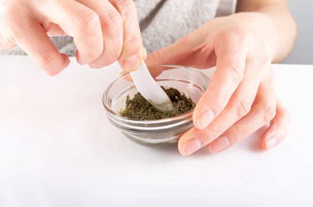 Mix cosmetics in a glass container. Green powder in a glass dish. White background. - Φωτογραφία, εικόνα