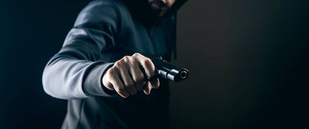 un uomo che tiene una pistola su uno sfondo scuro - Foto, immagini