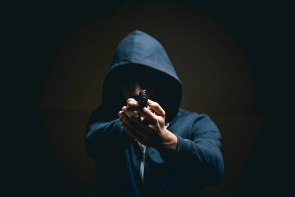 ein Mann mit einer Pistole auf dunklem Hintergrund - Foto, Bild