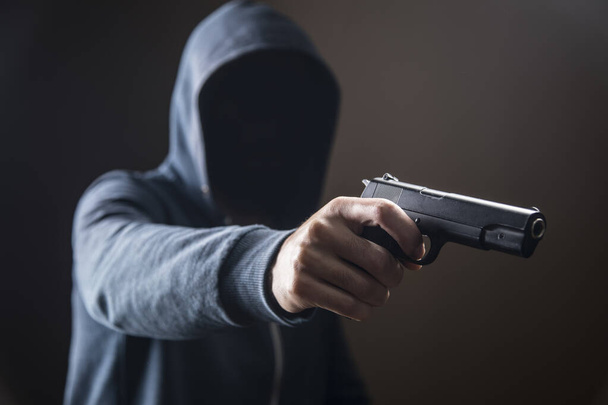 a man holding a pistol on a dark background - Photo, image