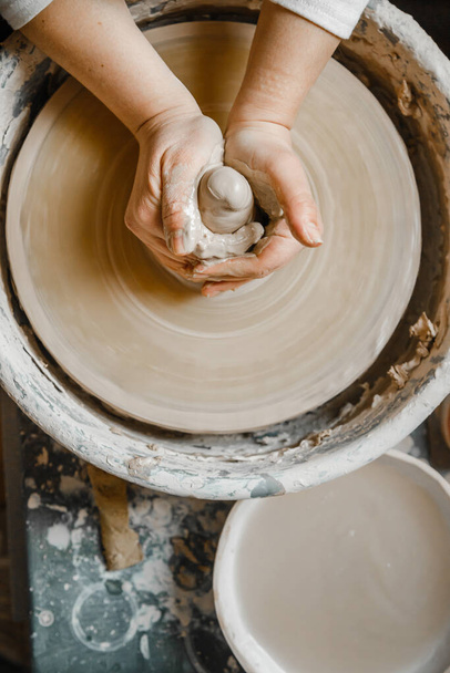 Potter ragazza scolpisce tazza di argilla sulla ruota del vasaio. Laboratorio di ceramica nel pomeriggio - Foto, immagini