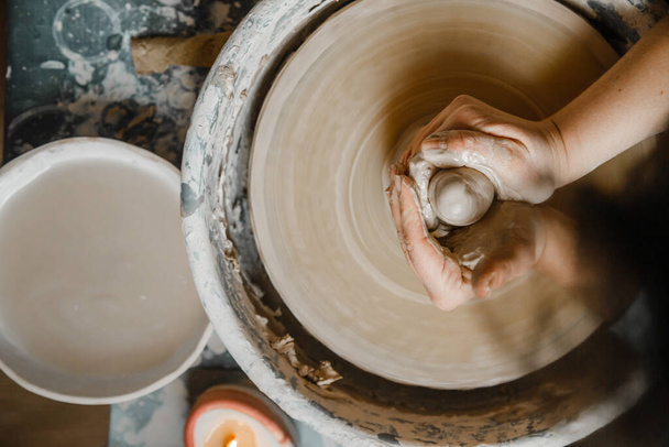 Potter girl sculpte tasse d'argile sur la roue du potier. Atelier de poterie en après-midi - Photo, image