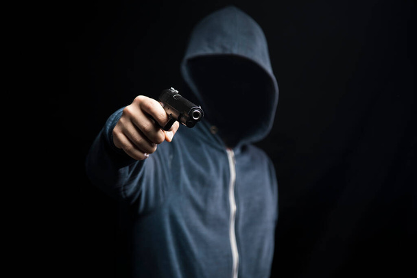un hombre sosteniendo una pistola sobre un fondo oscuro - Foto, Imagen