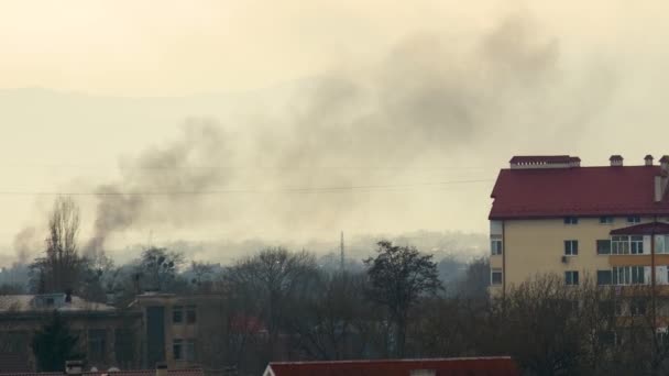 Silný černý kouř stoupá mezi budovami v rezidenční čtvrti. - Záběry, video
