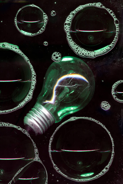 黒い背景に隔離されたガラス表面上の石鹸泡。暗い夜の光。アイデア電球抽象照明装飾。ナイトクラブ抽象壁紙 - 写真・画像