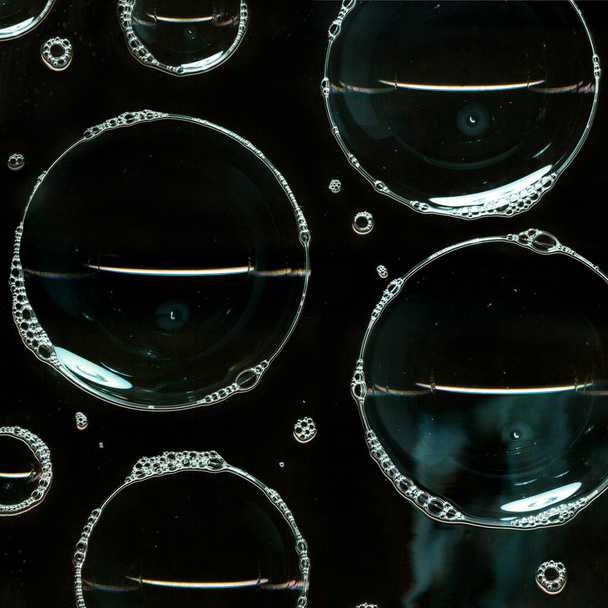 Мыльные пузыри пены на стеклянной поверхности изолированы на черном фоне. Свет в темной ночи. Абстрактное освещение. Ночной клуб абстрактных обоев - Фото, изображение
