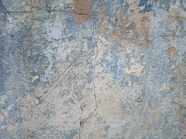 Concrete wall of an old house, painted with light blue paint, cracked, peeling and weathered - Фото, зображення
