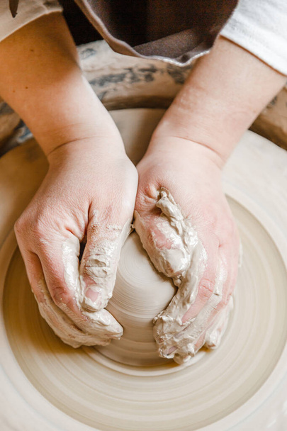 ポッターの女の子は陶芸家の車輪の上の粘土からカップを彫刻します。午後の陶芸教室 - 写真・画像