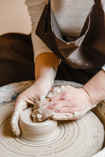 Töpfermädchen meißelt Becher aus Ton auf Töpferscheibe. Töpferwerkstatt am Nachmittag - Foto, Bild