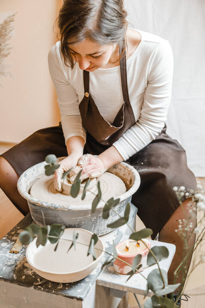Potter girl sculpte tasse d'argile sur la roue du potier. Atelier de poterie en après-midi - Photo, image