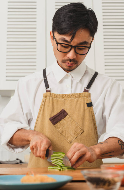 Sushi maestro chef rebanada de pepino fresco en la tabla de cortar en la cocina. Cuchillo en movimiento - Foto, imagen