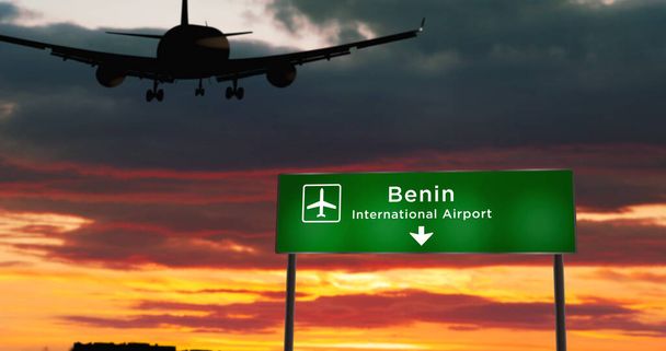 Silueta de avión aterrizando en Benin, Nigeria. Llegada a la ciudad con letrero de dirección del aeropuerto y puesta de sol en segundo plano. Concepto de viaje y transporte 3d ilustración. - Foto, imagen