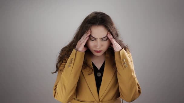 Izolovaný portrét mladé ženy trpící bolestí hlavy a dotýkající se spánků prsty ve zpomalení - Záběry, video