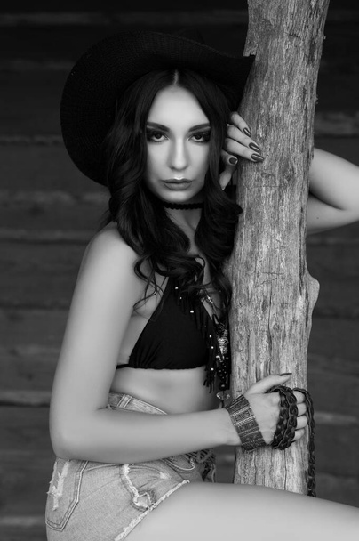 Beautiful sexy brunette girl dressed in cowboy style of wild west posing outdoors - Fotó, kép