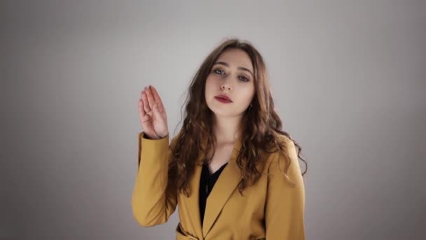 Retrato de una joven mujer irritada haciendo bla bla signo por su mano sobre fondo blanco en un slow mo - Metraje, vídeo
