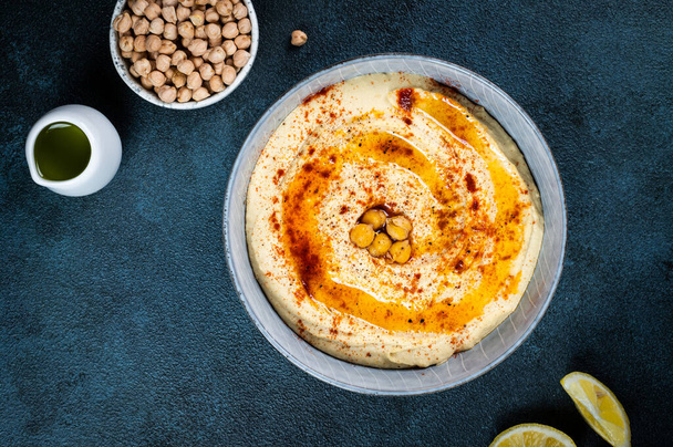 Entrée traditionnelle du Moyen-Orient Hummus servi avec du citron et du tahini, assaisonné avec de l'huile d'olive extra vierge et du paprika dans une assiette en céramique. plat oriental. Plat végétarien. Trempette traditionnelle au pois chiche - Photo, image