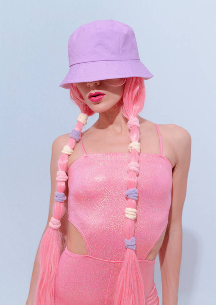 Model 90s party hip-hop style posing in white studio. Trendy pink jumpsuit, bucket hat and pink hair. Fashion unicorn Lady vibes - Foto, afbeelding