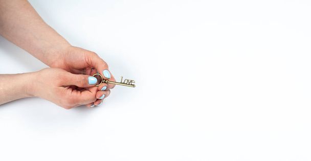 Manicure. Female hands with turquoise manicure. Old key in hand. Love. On white background. - Foto, Imagen