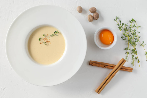 Tradycyjna włoska zupa w dużym białym talerzu z polami i składnikami - żółtko jaj, paluszki cynamonowe, tymianek i gałka muszkatołowa - Zdjęcie, obraz