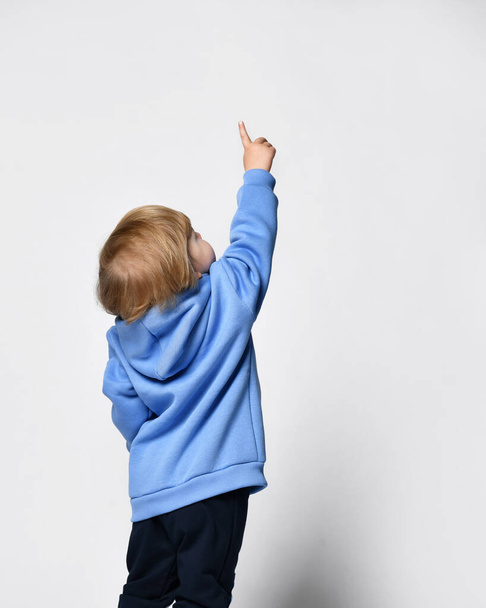 blond little boy in blue t-shirt posing on light background - Foto, Imagem