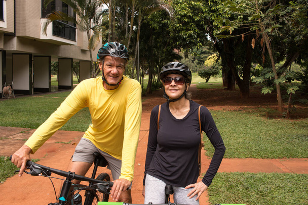 Couple d'âge mûr en plein air dans une zone urbaine sur leurs vélos - Photo, image