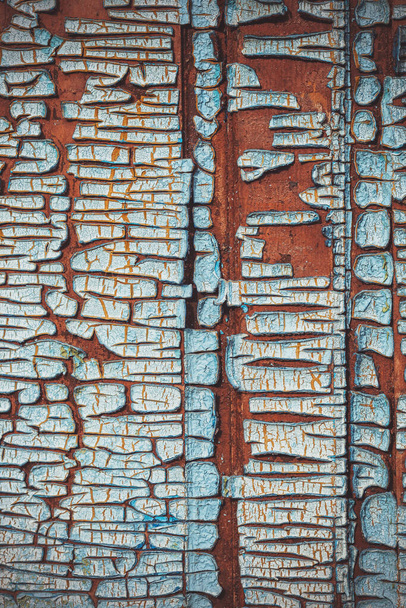 Egy fából készült ajtó töredéke. Régi festék. Megrepedt a festék. Törött festék egy fa felületen. A repedések szerkezete. A régi fa textúrája. Grunge textúra. Kék háttér - Fotó, kép