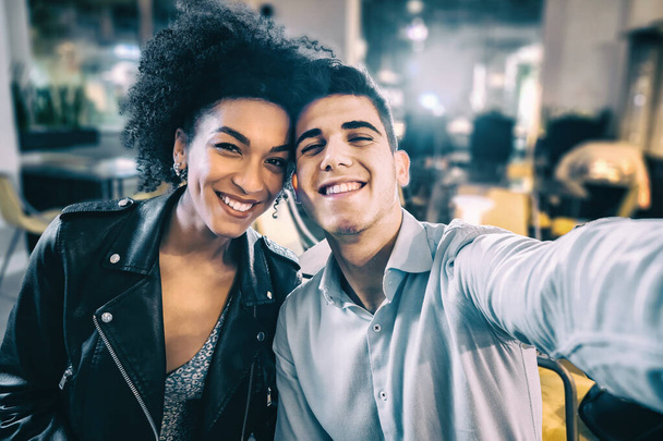Generatie z gelukkig multiraciaal koppel neemt selfie in het restaurant. Jongeren hebben plezier in het maken van zelfportretten met het smartphone concept. - Foto, afbeelding
