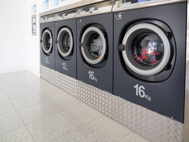 Rij wasmachines in een openbare wasserette. Reinigingsconcept - Foto, afbeelding
