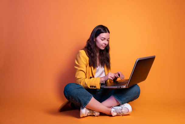 jeune femme en jaune fait des affaires sur un ordinateur portable, un pigiste ou un étudiant travaille à distance. - Photo, image