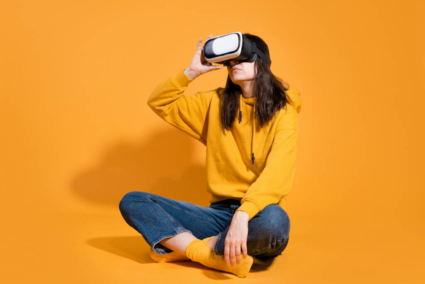 young woman with a virtual reality device on a yellow background. - Photo, image