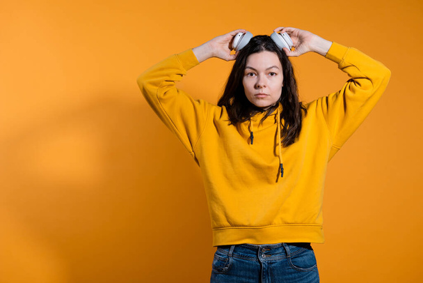 Music lovers enjoy music. A young woman in a yellow hoodie with white wireless headphones, - Fotó, kép