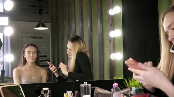 morena mujer asiática con maquillaje sentado en salón de belleza delante del espejo - Imágenes, Vídeo