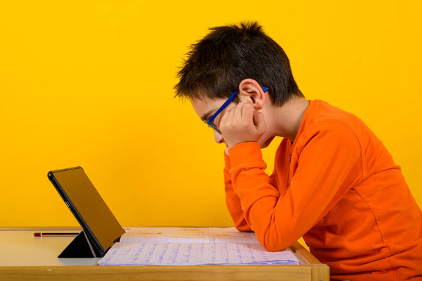 Das Kind hört eine Fernstunde mit dem Lehrer. gelber Hintergrund - Foto, Bild