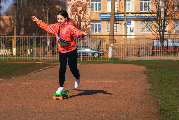 Teenager Mädchen im Urlaub in heller Kleidung fahren Skateboard oder Pennyboard im Park. Skateboarden ist eine großartige Möglichkeit, Ihre Gesundheit und Koordination zu verbessern. Aktives Kind für einen Spaziergang - Foto, Bild