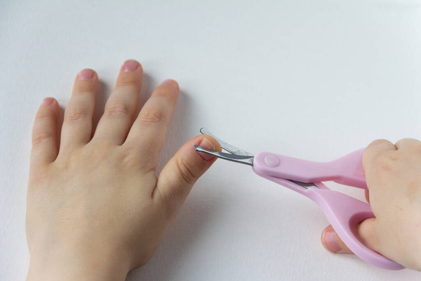 Ein kleines Kind verletzte sich am Daumen, als es versuchte, sich selbst die Nägel zu schneiden. - Foto, Bild