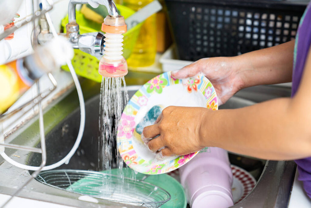 hautnah Dienstmädchen waschen einen Teller auf einer Spüle mit Seife und Wasser. - Foto, Bild