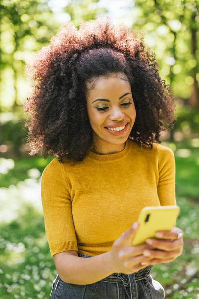 Bella e felice afro donna digitando sul cellulare. - Foto, immagini