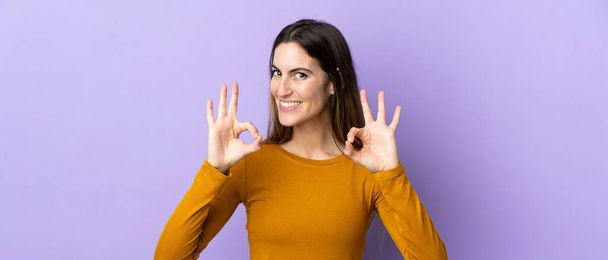 Nuori valkoihoinen nainen yli eristetty tausta osoittaa ok merkki kahdella kädellä - Valokuva, kuva