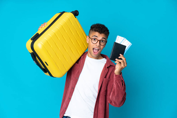 Fiatal brazil férfi elszigetelt háttér nyaralás bőrönddel és útlevéllel - Fotó, kép