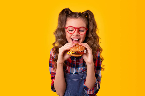 Happy girl biting delicious hamburger - Фото, изображение