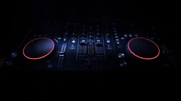 Concetto di musica da club. DJ console deejay-mixaggio scrivania in buio con luce colorata. Attrezzatura mixer stazione DJ di intrattenimento. Focus selettivo - Foto, immagini