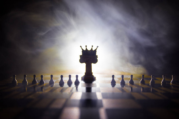 Beautiful crown miniature on chessboard. chess board game concept of business ideas and competition and strategy ideas concept. Chess figures on a dark background with smoke and fog. Selective focus - Photo, image