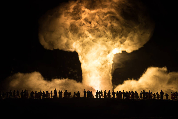 Πυρηνικός πόλεμος. Έκρηξη πυρηνικής βόμβας. Δημιουργική διακόσμηση σε σκούρο χρώμα. Άνθρωποι που βλέπουν ένα γιγαντιαίο μανιταρένιο σύννεφο ατομικής έκρηξης. Επιλεκτική εστίαση - Φωτογραφία, εικόνα