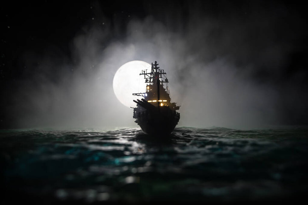 Concetto di guerra. Scena di battaglia notturna in mare. Drammatico effetto luna decorato. Silhouette della nave da battaglia di notte. Decorazione da tavolo creativa in miniatura. Focus selettivo - Foto, immagini