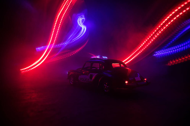 Auto della polizia a caccia di una macchina di notte con sfondo nebbia. 911 Auto della polizia di emergenza che accelera sulla scena del crimine. Decorazione creativa. Focus selettivo - Foto, immagini