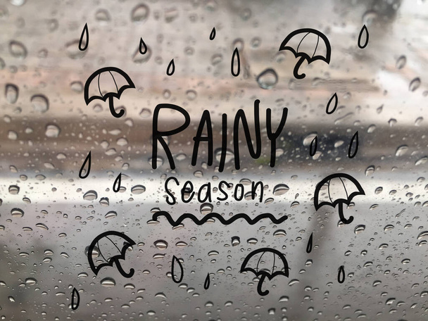 esős évszak betűző rajzfilm esernyők a háttérben cseppek üveg - Fotó, kép