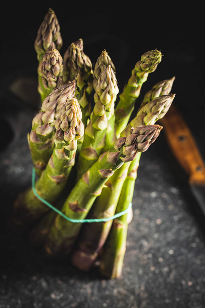 Fresh raw uncooked green asparagus on black table. - 写真・画像