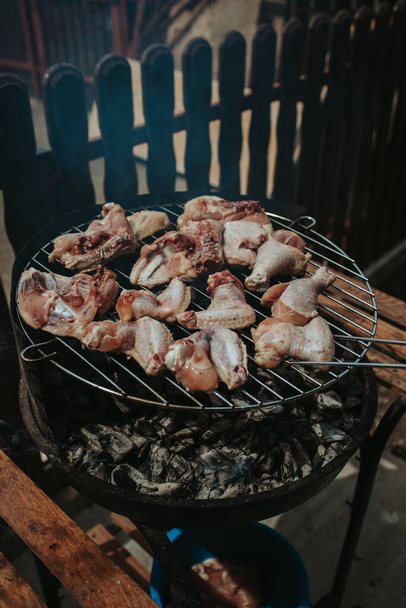 A vertical shot of delicious chicken breast and drumsticks cooking over a fire pit in a backyard - Valokuva, kuva