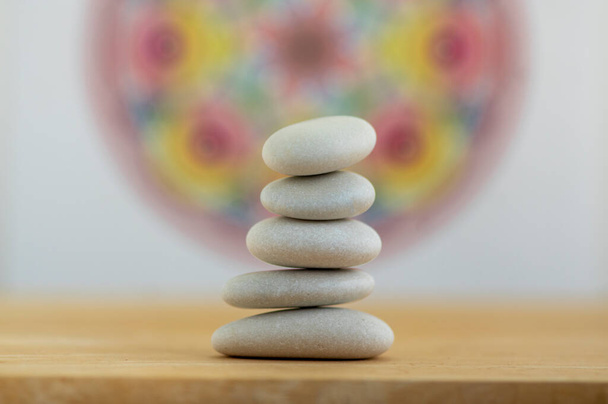 Stone cairn on white and colorfull red yellow mandala background, five stones tower, simple poise stones, simplicity harmony and balance, rock zen sculpture - Photo, Image